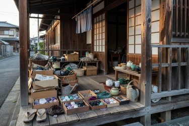 A modest wooden Japanese suburban porch cluttered with everyday household objects