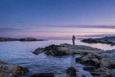 A tranquil rocky coastal bay under an evening Scottish twilight sky